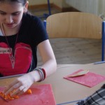Schülerin hilft den Projektmitgliedern, indem sie Gemüse schneidet
